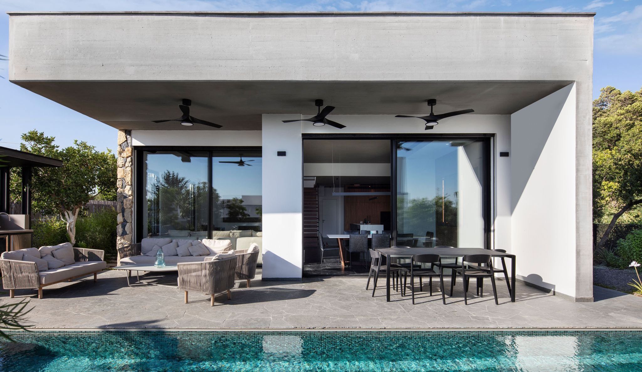 The villa and its large covered terrace, with outdoor lounge and dining table, and the private pool in the foreground