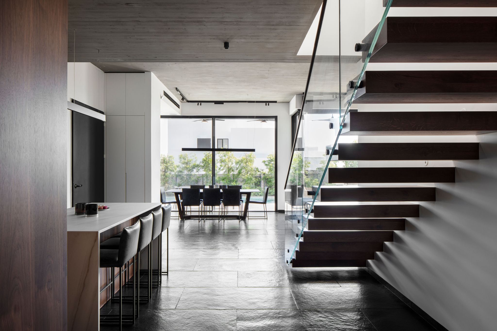 Open-plan living area with dining space and a wood-and-glass floating staircase