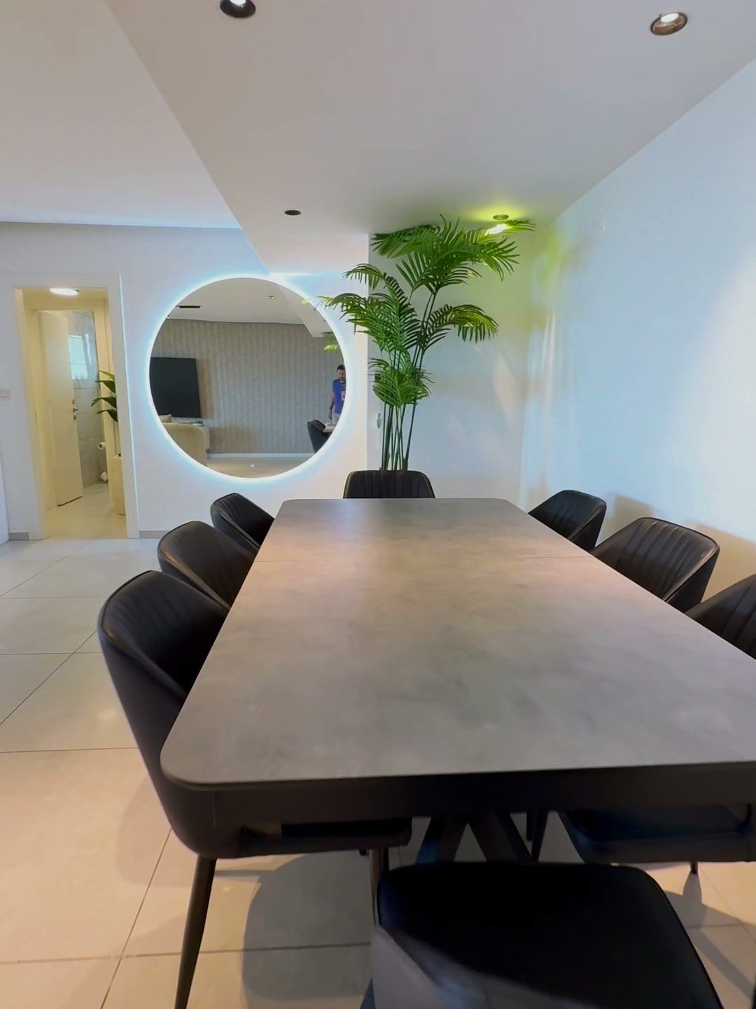 Coin repas avec grande table et miroir rond éclairé