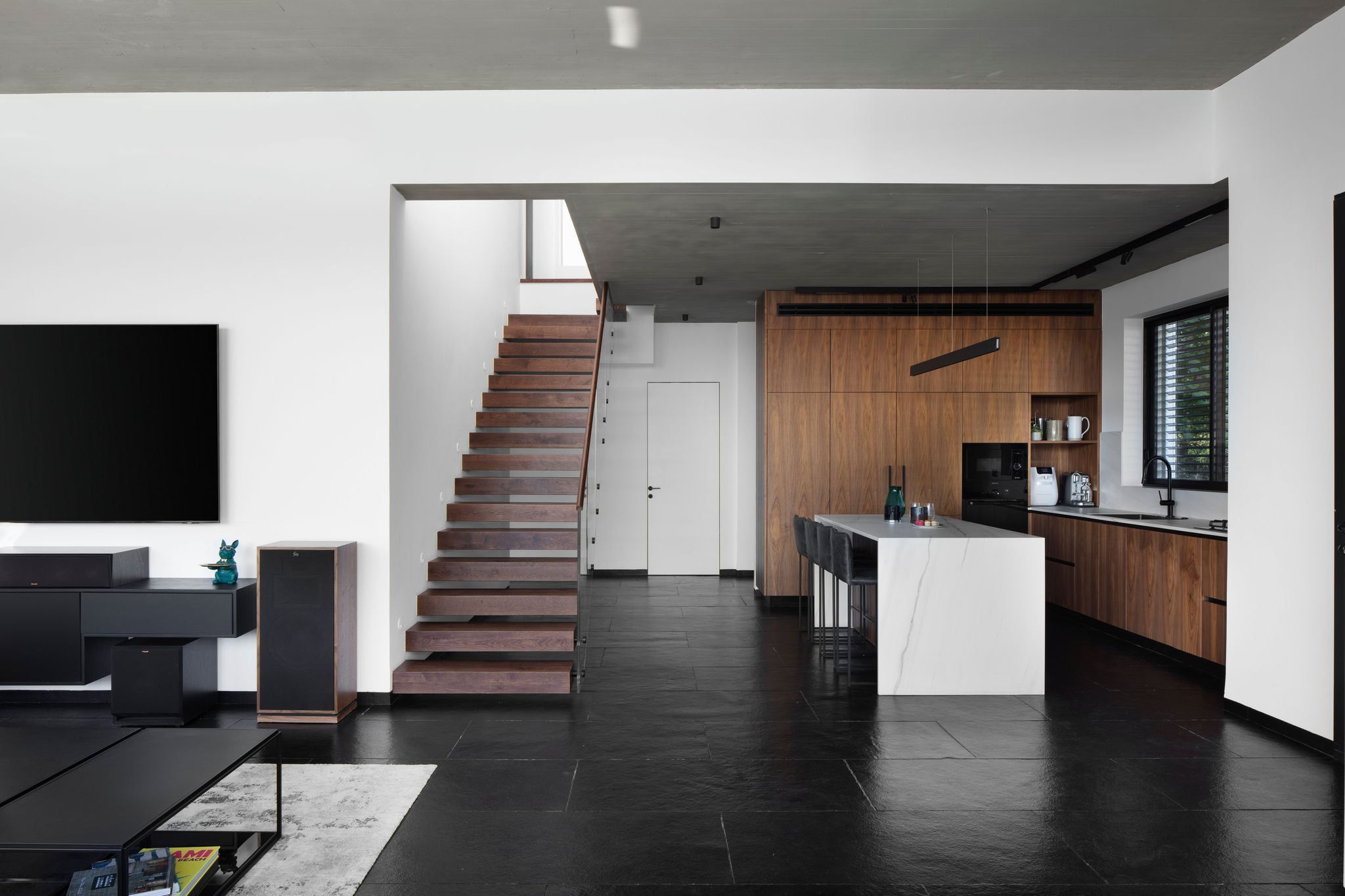 Wood-panelled kitchen and white island beside the floating staircase
