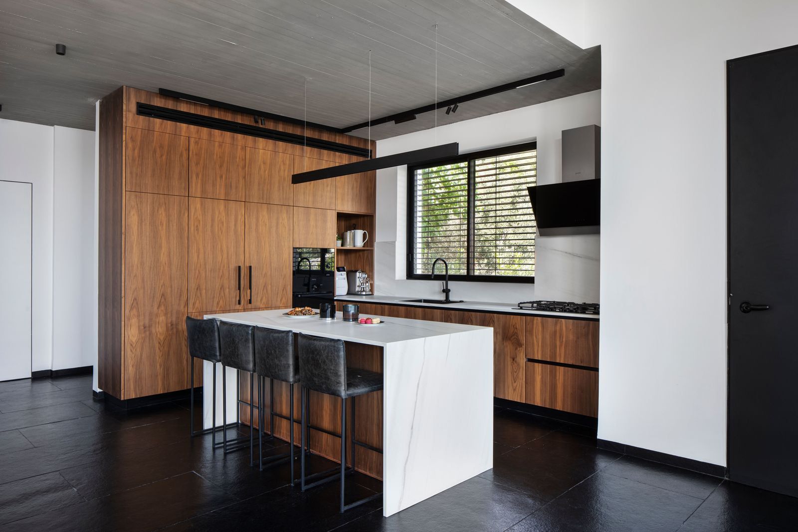White marble kitchen island with bar stools under a concrete ceiling