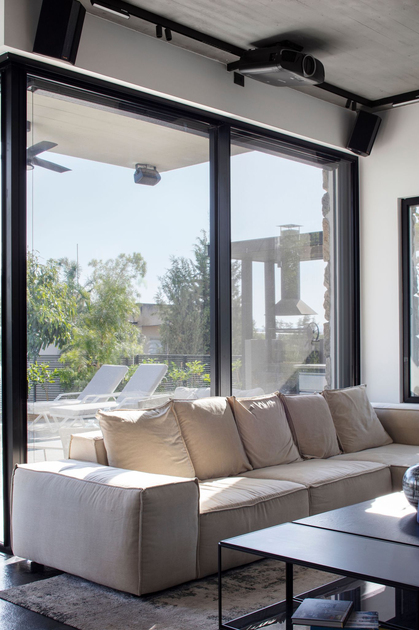 Living room with a large sofa facing glass doors onto the pool
