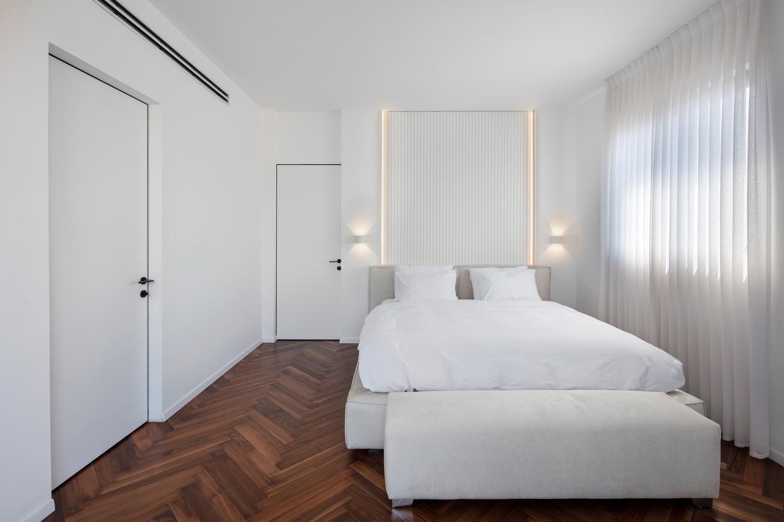 Bedroom with herringbone parquet and a backlit headboard