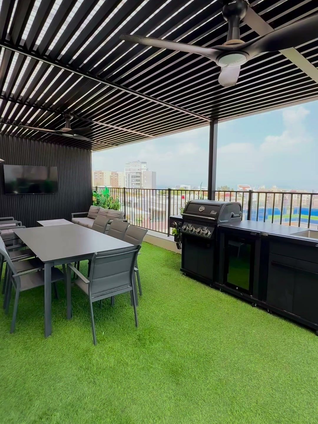 Espace extérieur sous pergola, avec table, barbecue et gazon synthétique