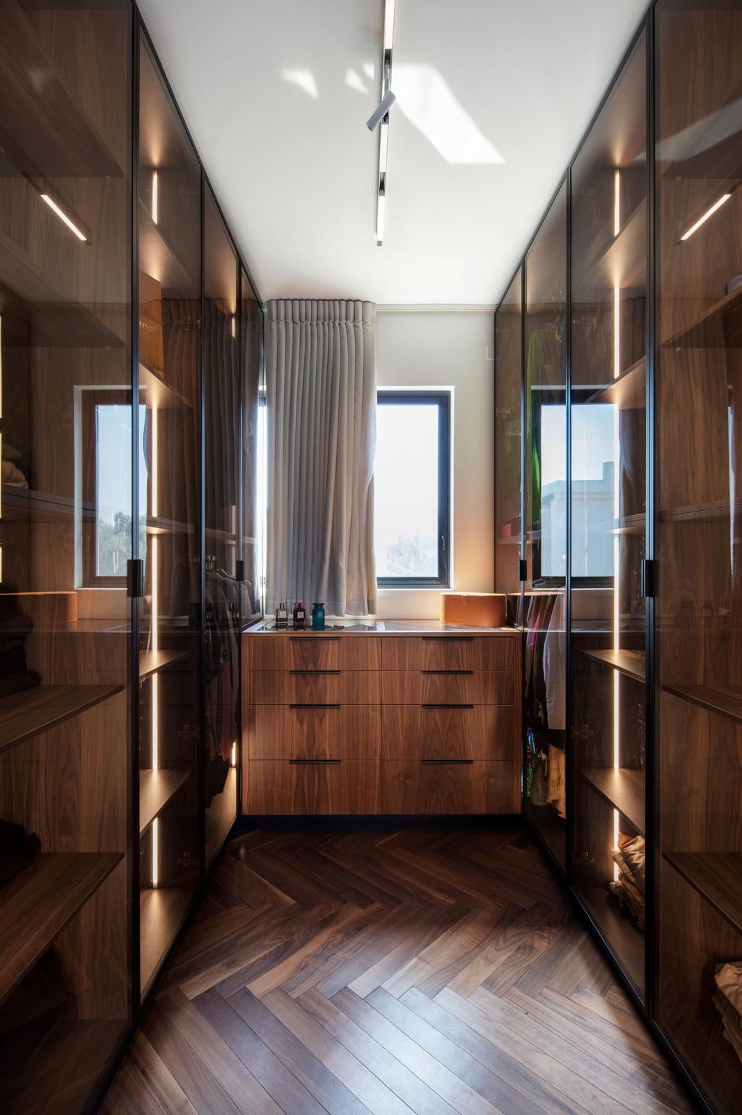 Wood walk-in wardrobe with lit glass-fronted cabinets