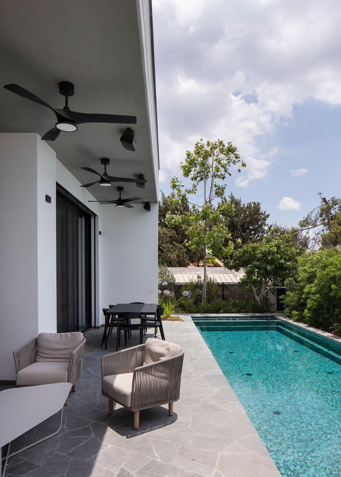 Covered terrace and pool surrounded by greenery